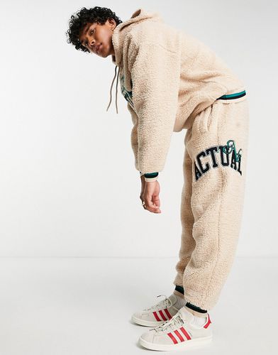 ASOS Actual - Pantalon de jogging décontracté d'ensemble en imitation peau de mouton à logo appliqué et liseré - Neutre - Asos Design - Modalova
